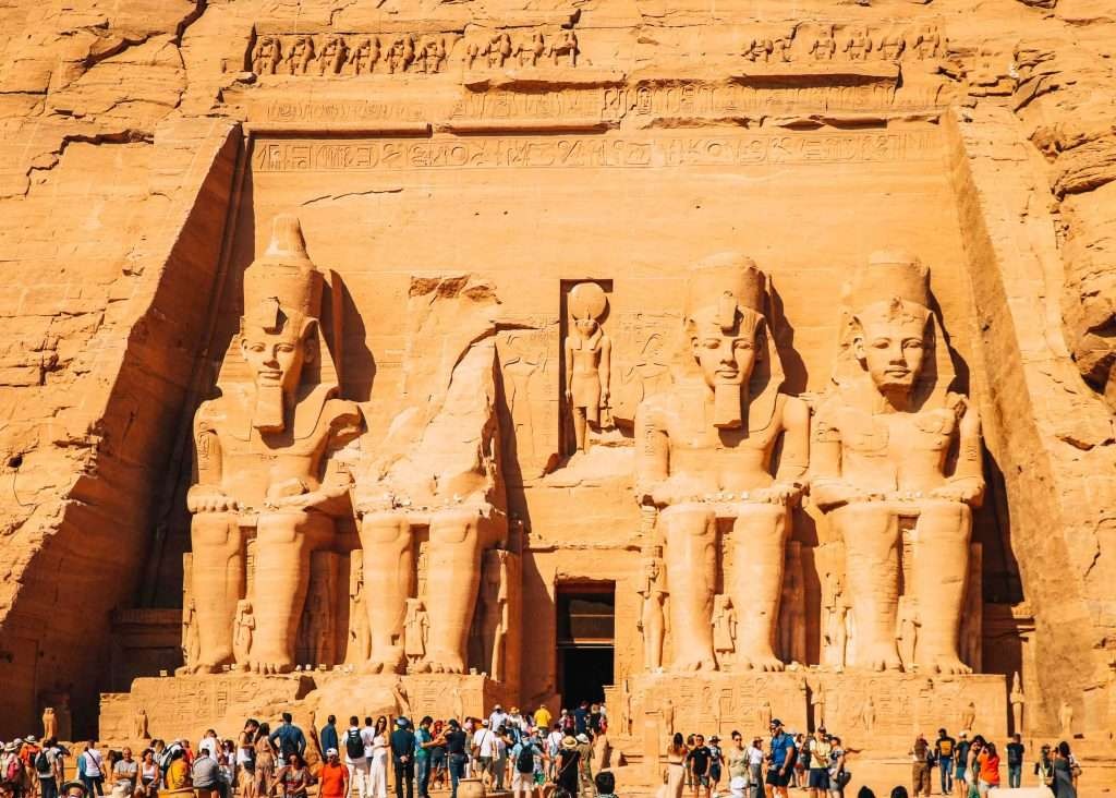 The Great Temple at Abu Simbel in Egypt is admired by dozens of people standing in front of it, looking like ants in front of this giant temple complex