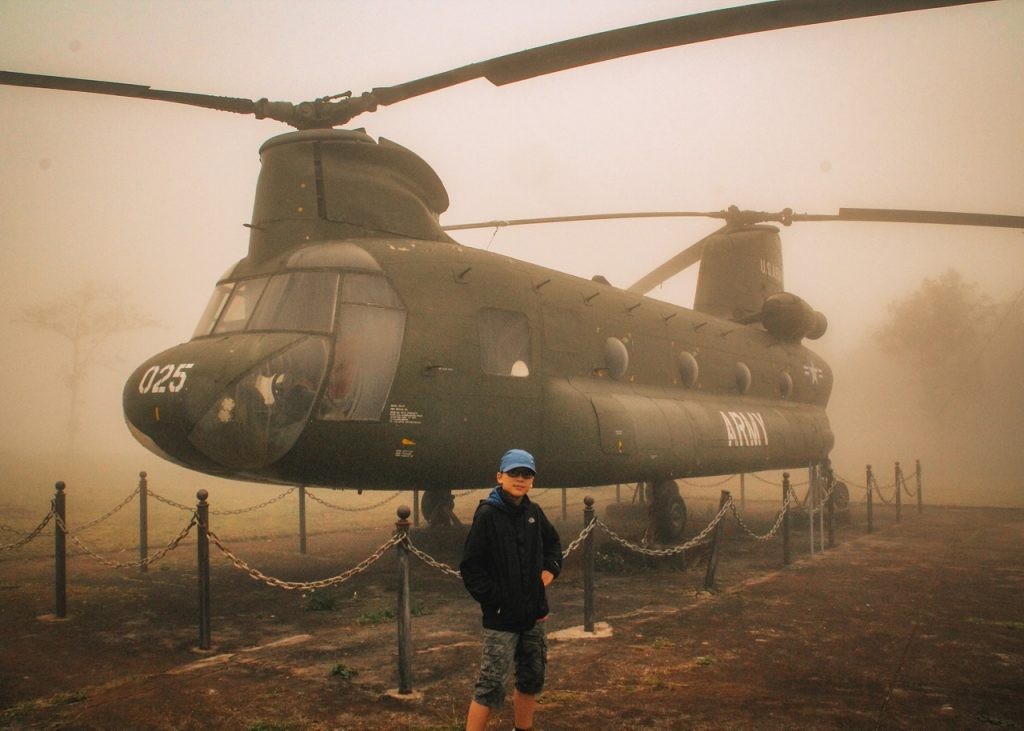 a boy poses in front of a helicopter at the Khe Sanh Combat Base at the former DMZ in Vietnam