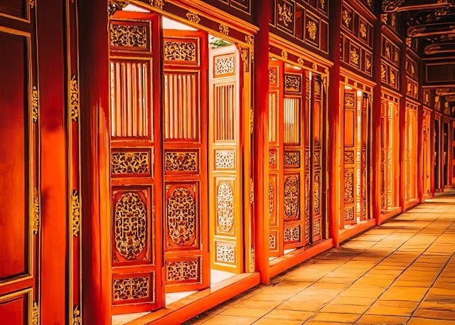 Ancient chinese wooden red doors, partially opened, in the Imperial City in Hue - Vietnam