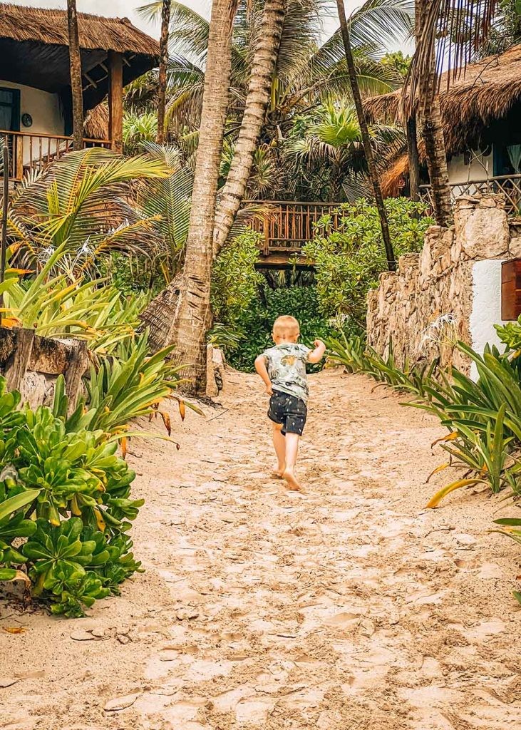 A little boy running through the sand at a beach club in Tulum - Mexico